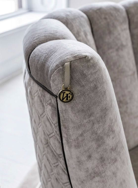 Grey tufted sofa with logo charm on zipper pull