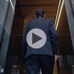 Businessman walking in modern office corridor, play icon overlay