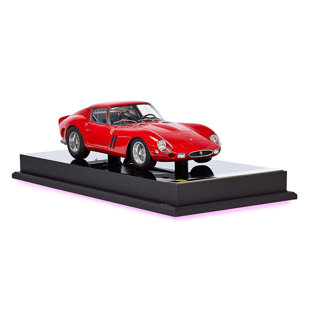 Red classic sports car model on display stand.