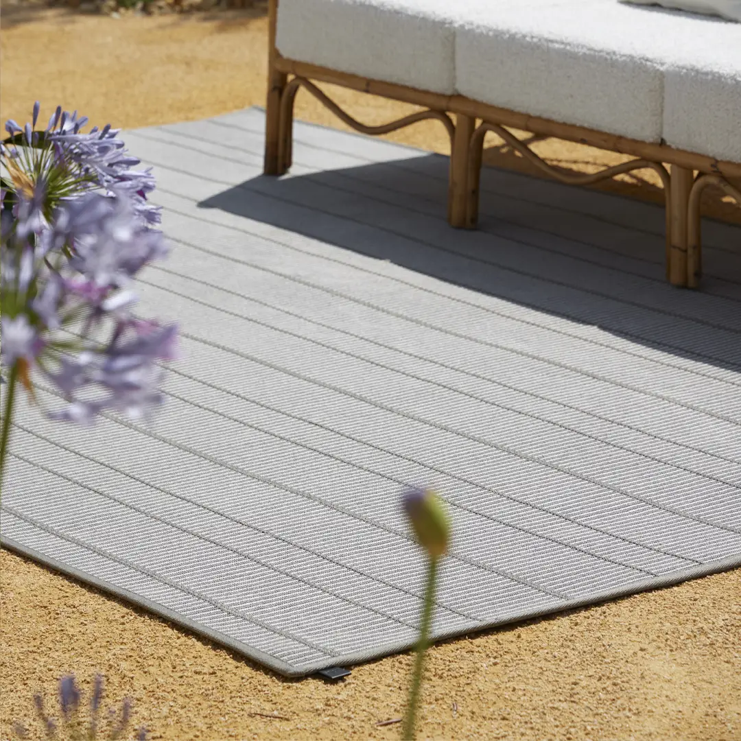 LYRA_3 Outdoor garden bench on gray striped rug with flowers