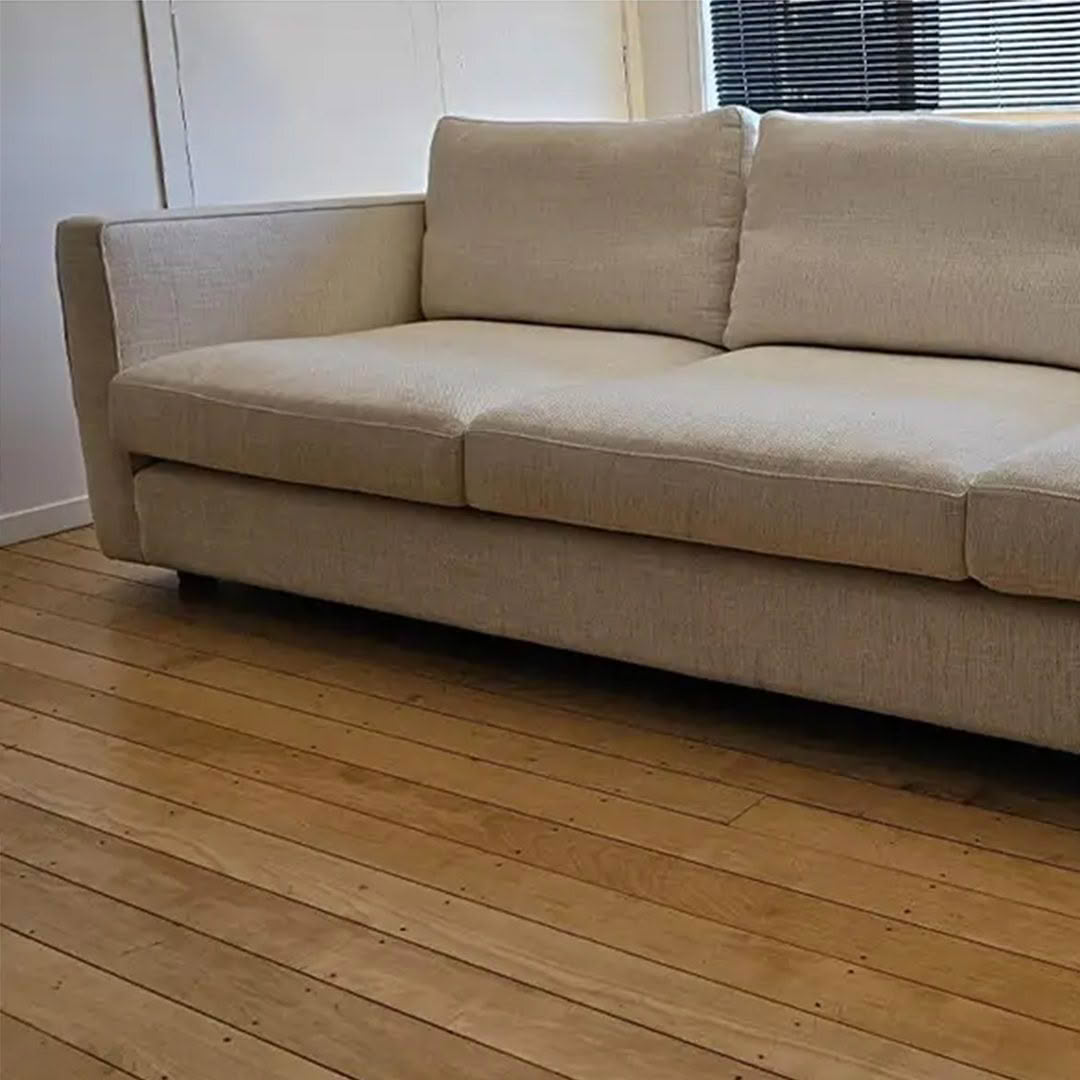 Beige sofa on hardwood floor near window