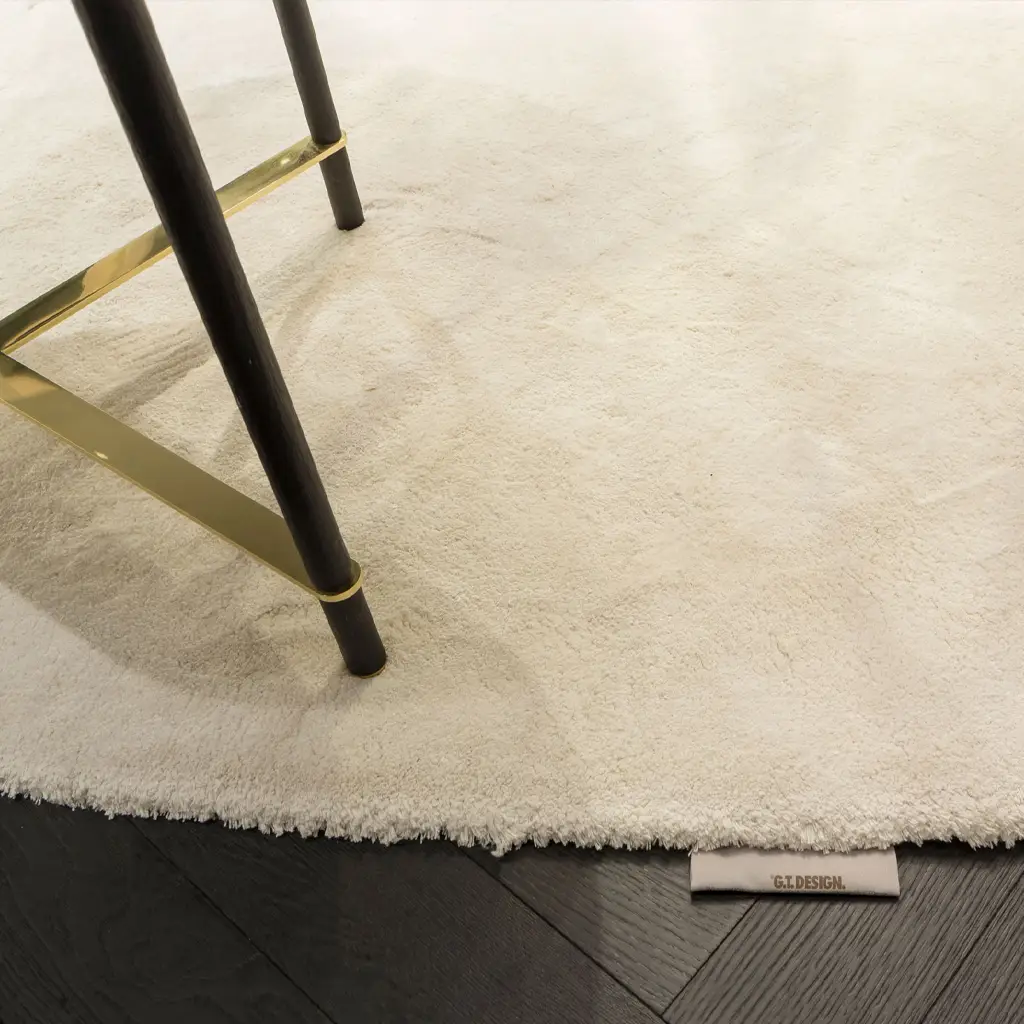 Black chair leg on white fluffy rug, wood floor beneath