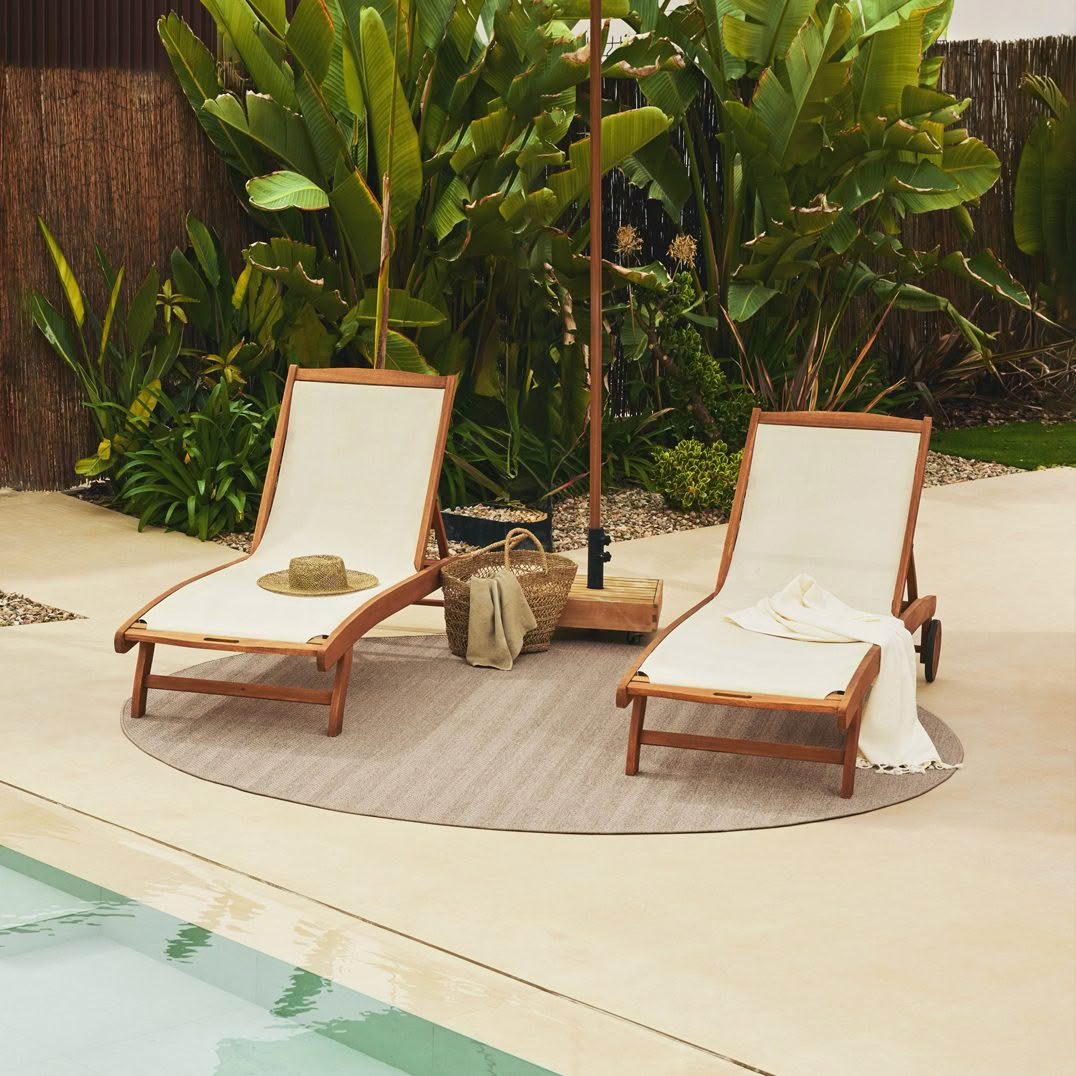 Two lounge chairs beside pool with tropical plants
