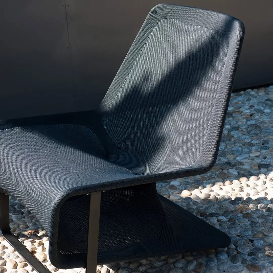 Modern gray chair on pebble ground in sunlight