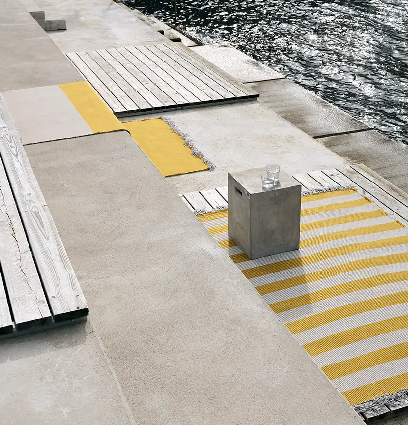 Modern waterfront seating with concrete cube and striped rug