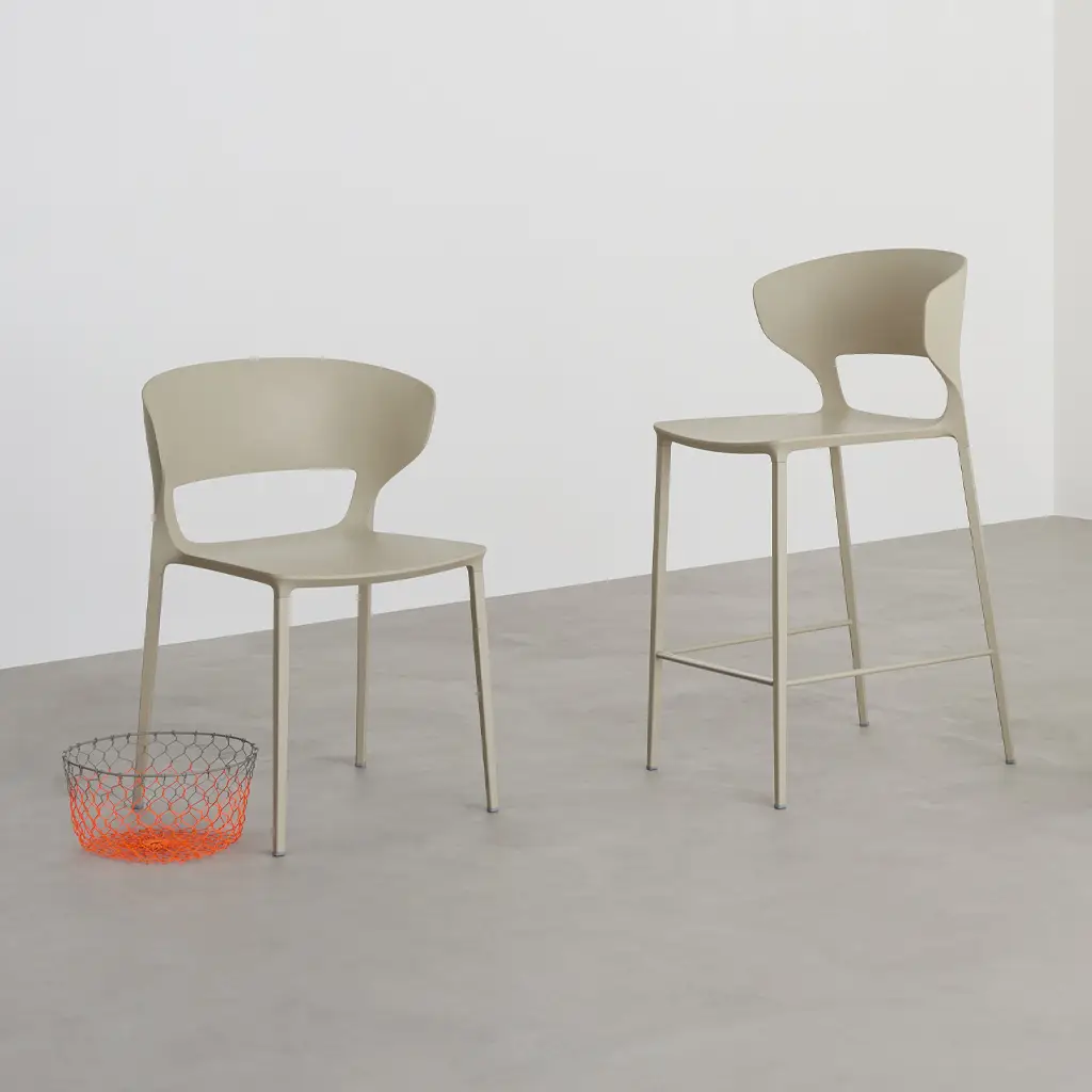 Two modern chairs and orange mesh basket on gray floor.