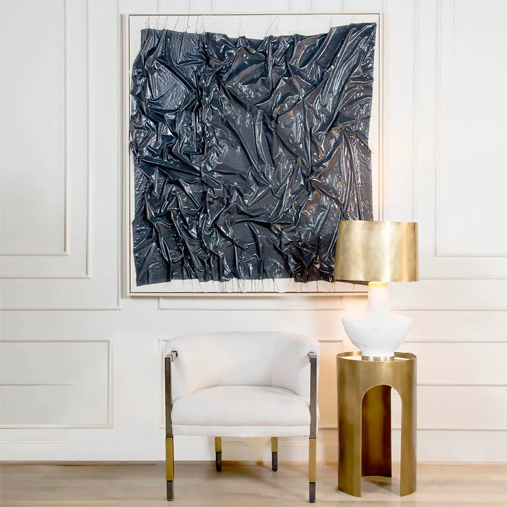 Abstract black sculpture on wall above elegant chair and lamp