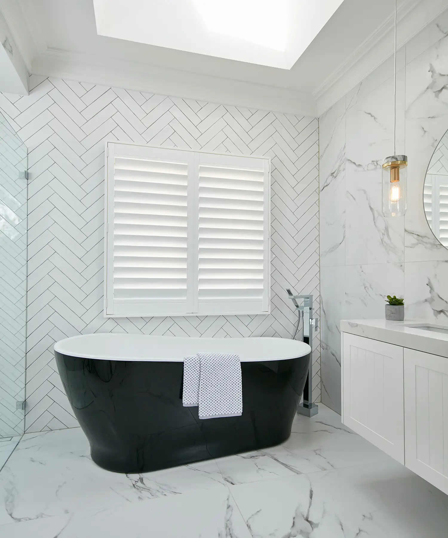 Elegant bathroom with black freestanding tub and marble tiles