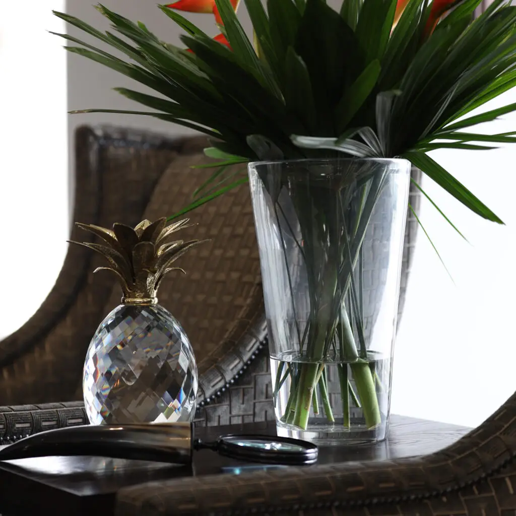Crystal pineapple and plants on wicker table.
