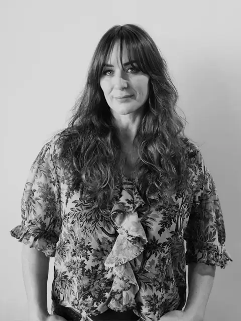 Woman in floral shirt smiling slightly, black and white photo
