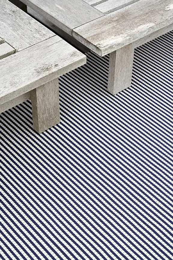 Weathered wooden bench on striped blue and white rug