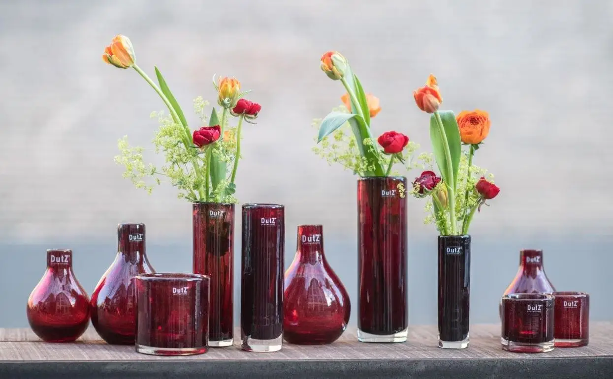 Colorful tulips in assorted red glass vases on table