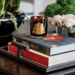 Lit candle on books with flowers in background