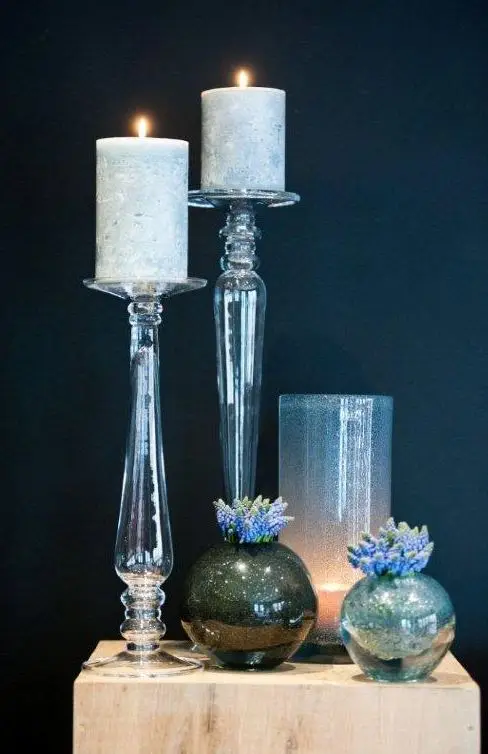 Lit candles in glass holders with decorative spheres