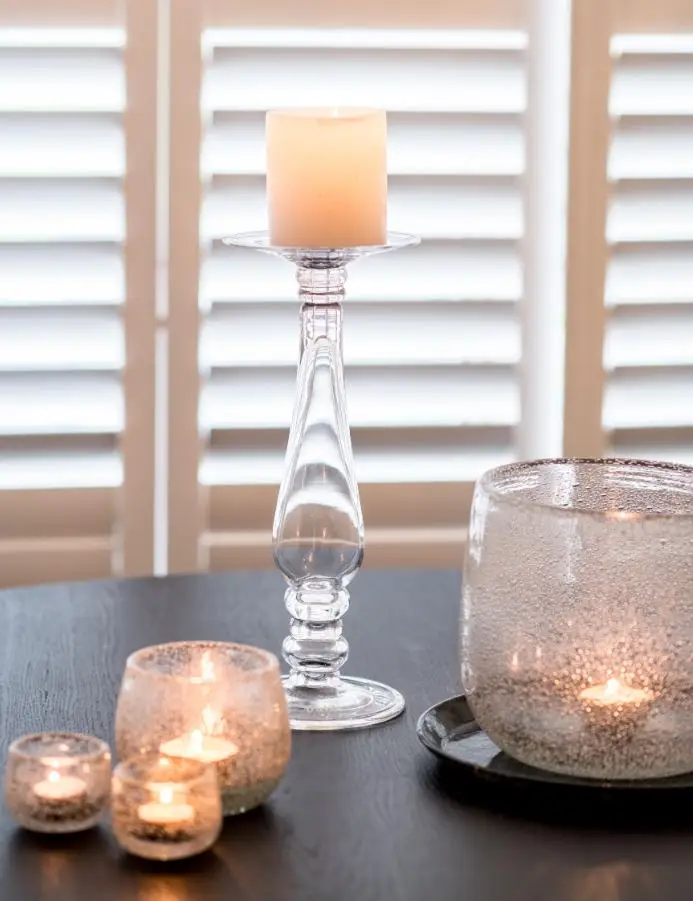 Elegant candle arrangement on table with blinds behind
