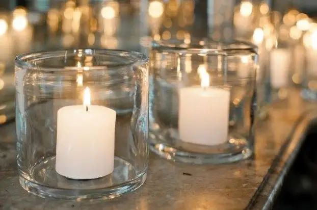 Two lit candles in clear glass holders on table