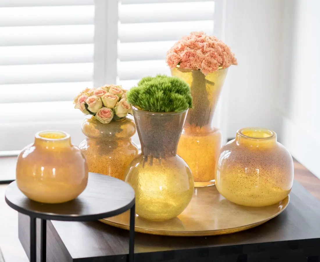 Elegant floral arrangements in yellow glass vases on table