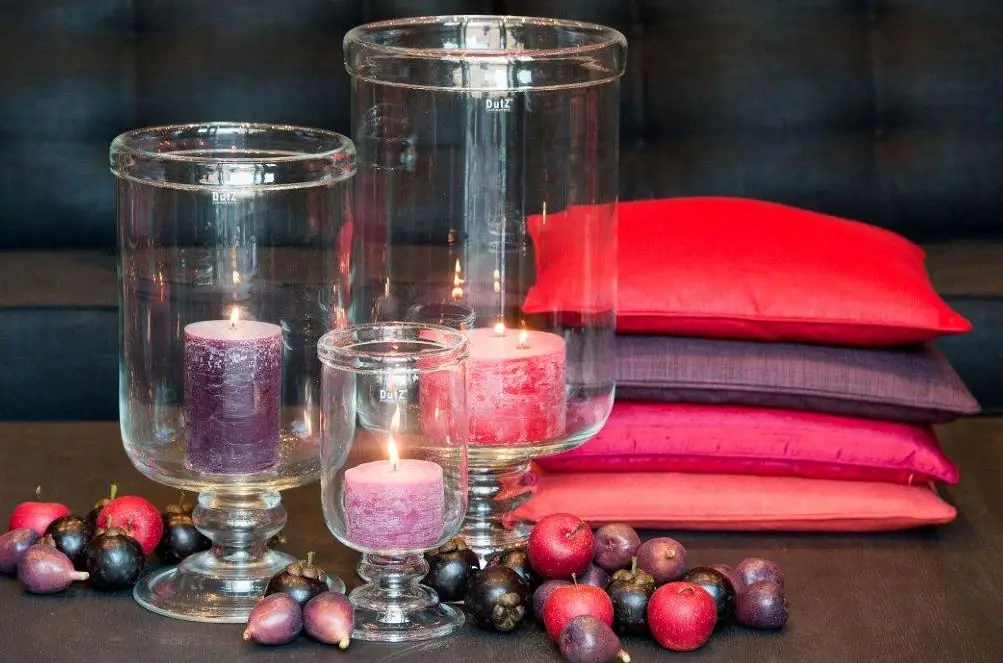 Candles in glass holders with colorful cushions and berries