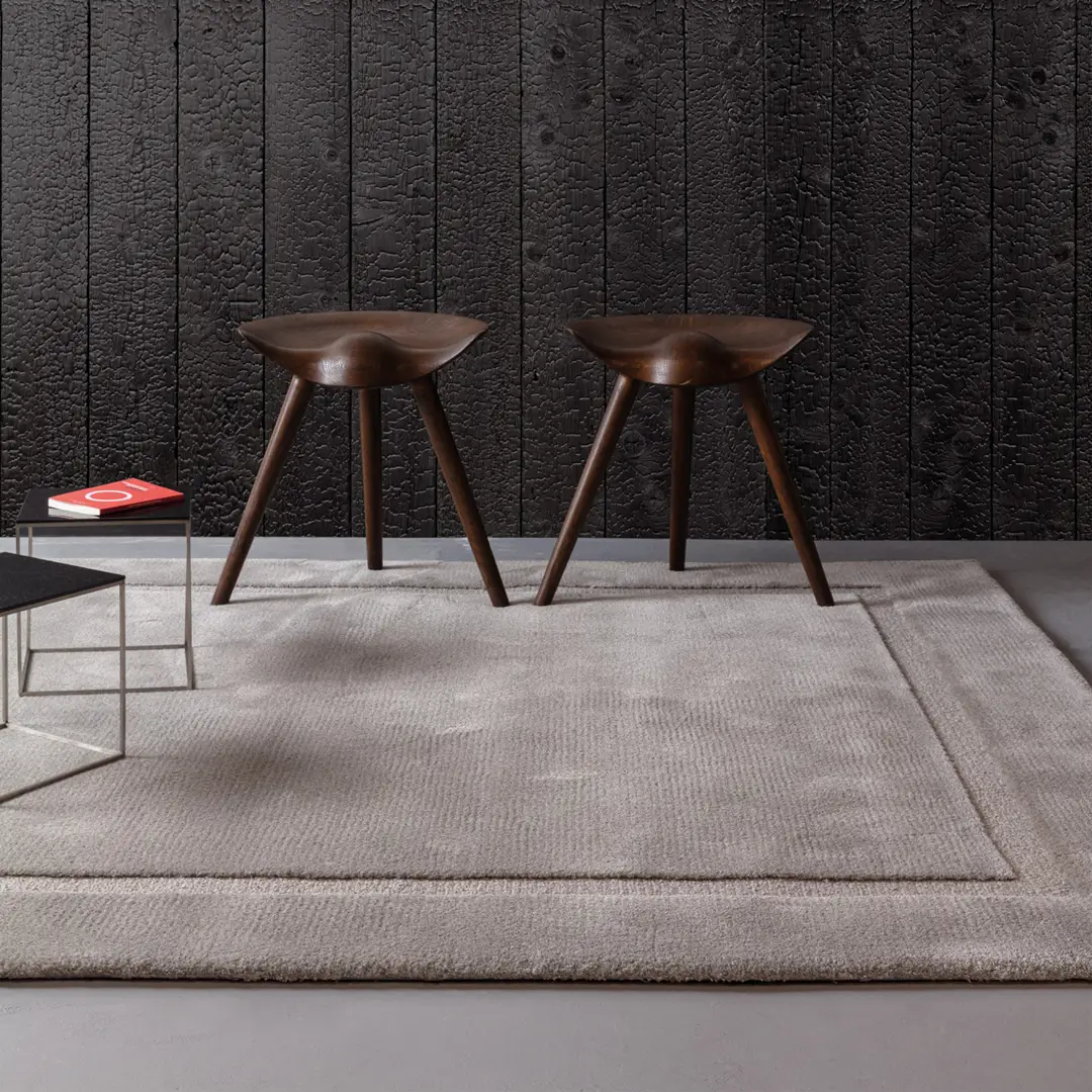 Two modern wooden stools on a textured gray rug