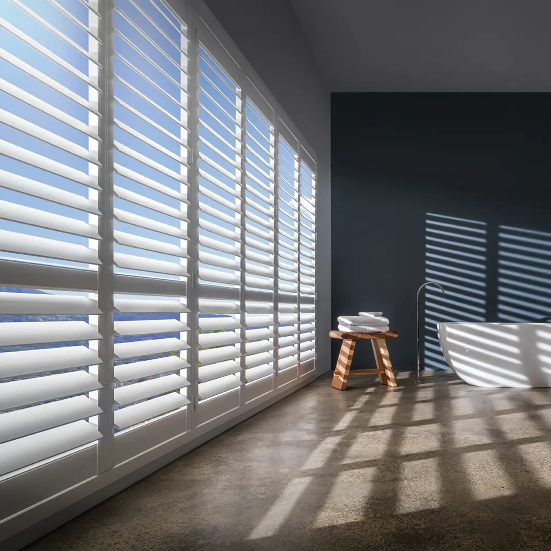 Sunlit modern bathroom with white shutters and bathtub