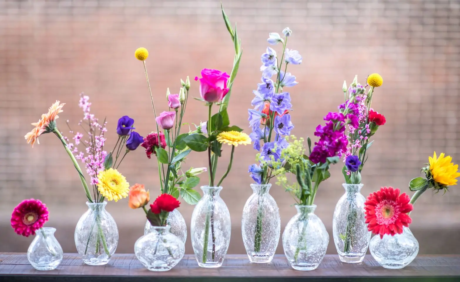 Colorful flowers in glass vases on wooden table