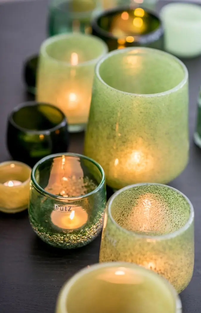 Variety of lit candles in colorful glass holders