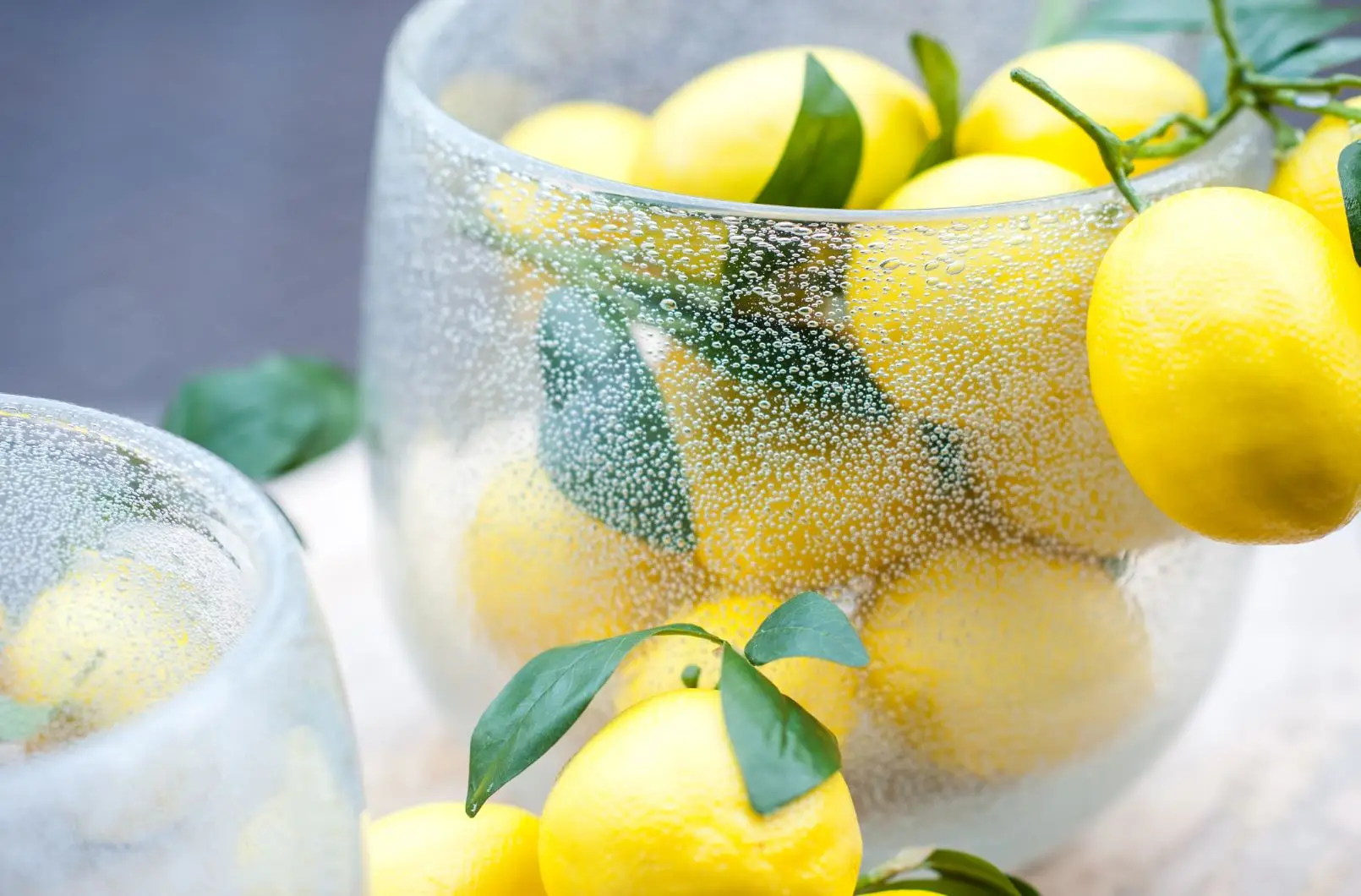Fresh lemons with leaves in a glass jar