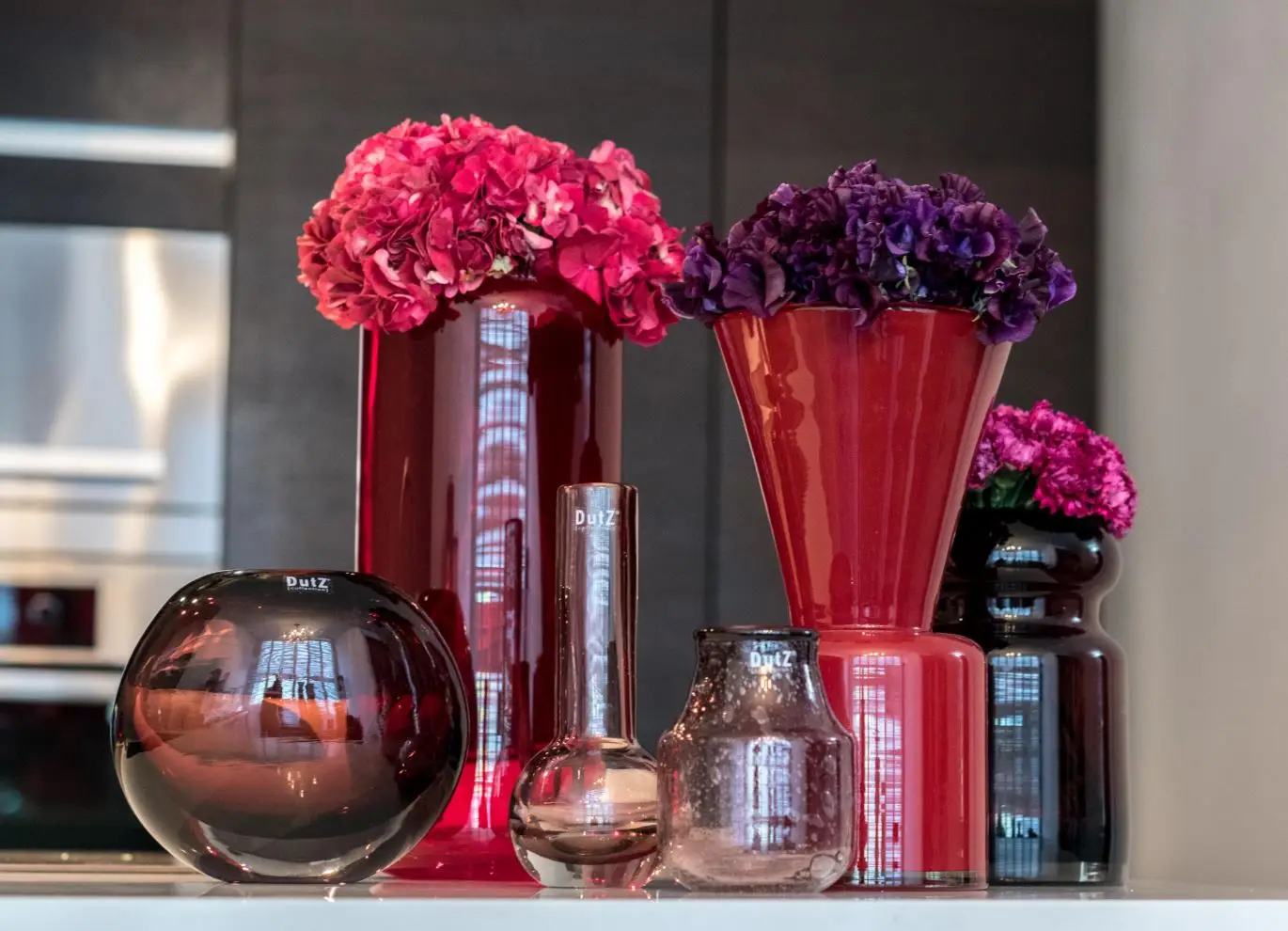 Assorted colorful vases with vibrant flowers on display