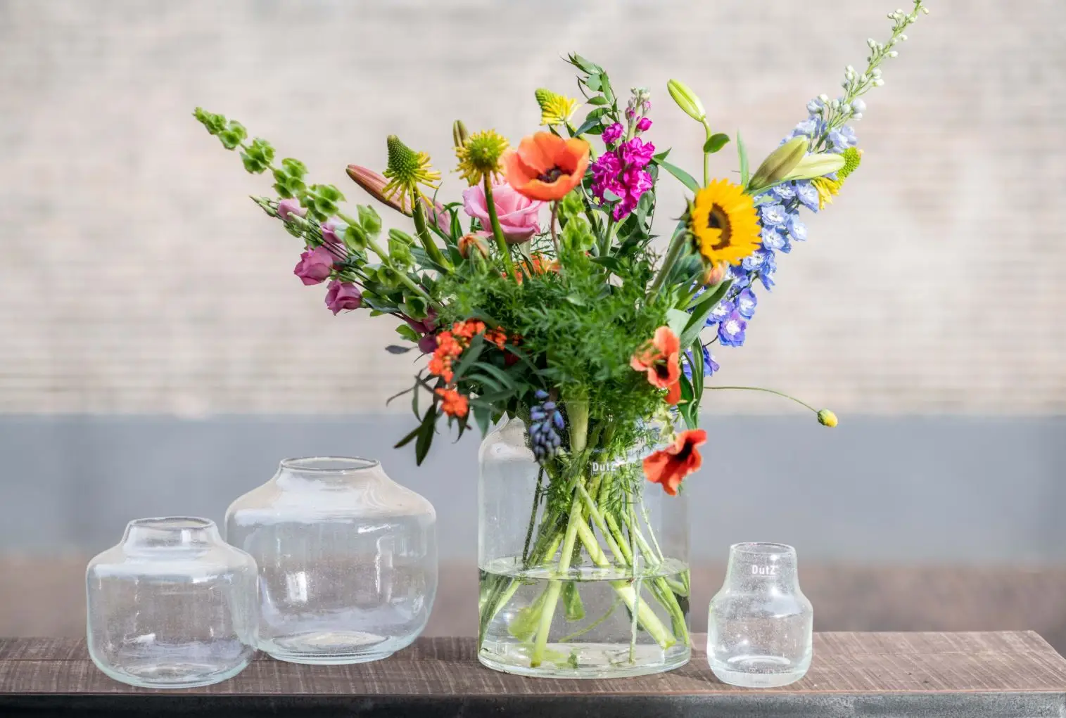 Colorful bouquet in glass vase with empty jars nearby