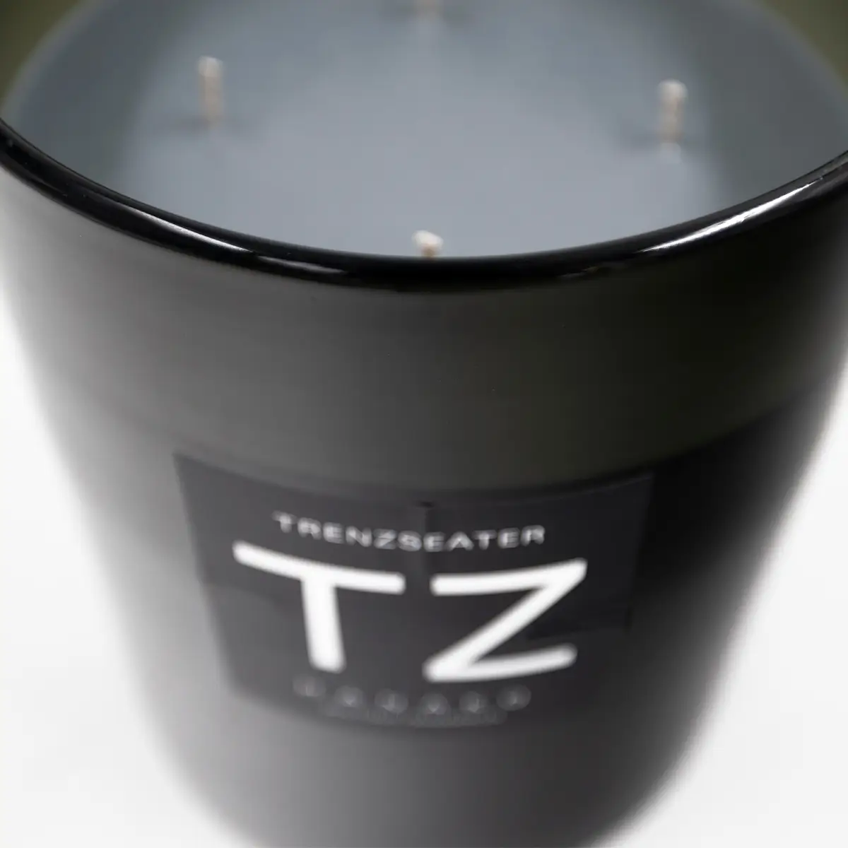 Close-up of black scented candle with 'TZ' logo