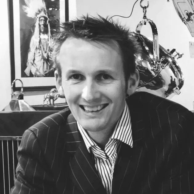 Smiling man in striped suit before native American painting