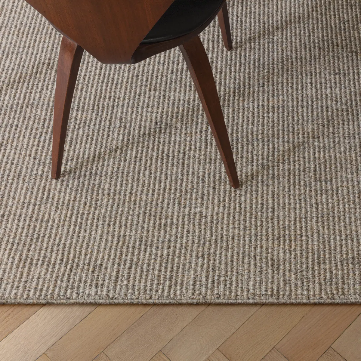 Kigali_Golden_Ray Woven rug with wooden chair leg close-up