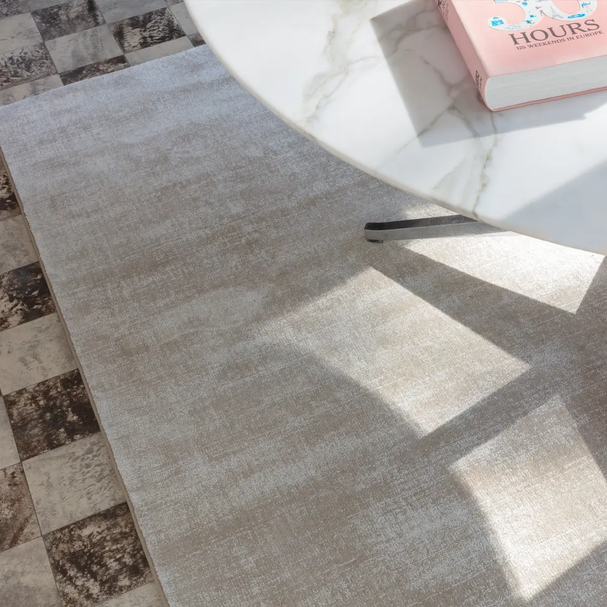 Round marble table on patterned rug in sunlit room