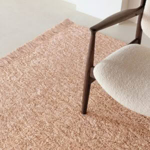 Minimalist chair on textured pink rug in neutral room