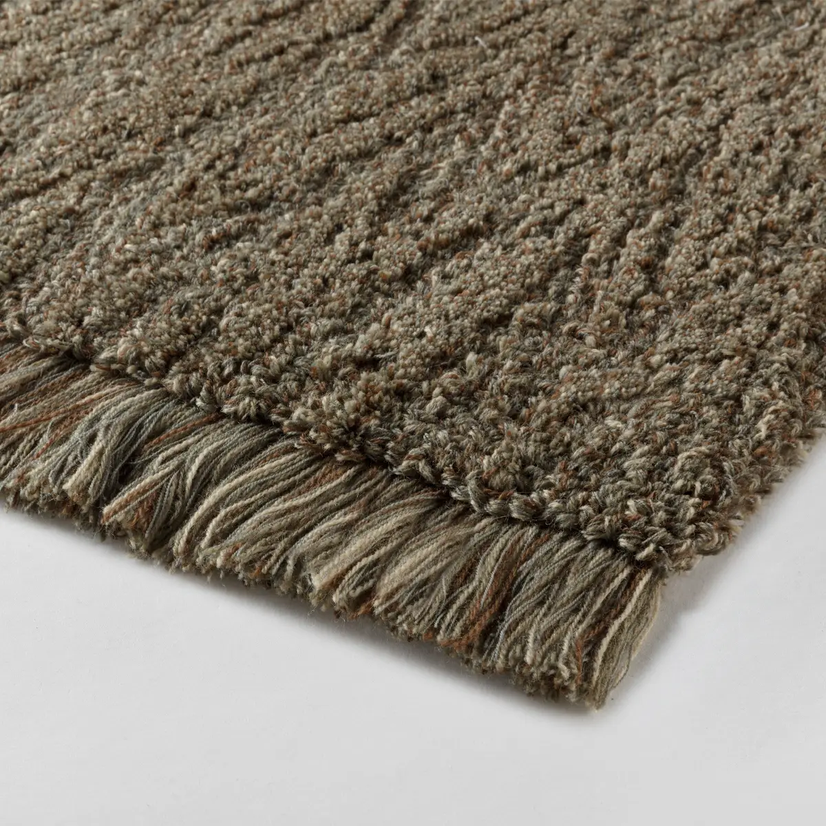 Close-up of textured gray handwoven rug with fringe