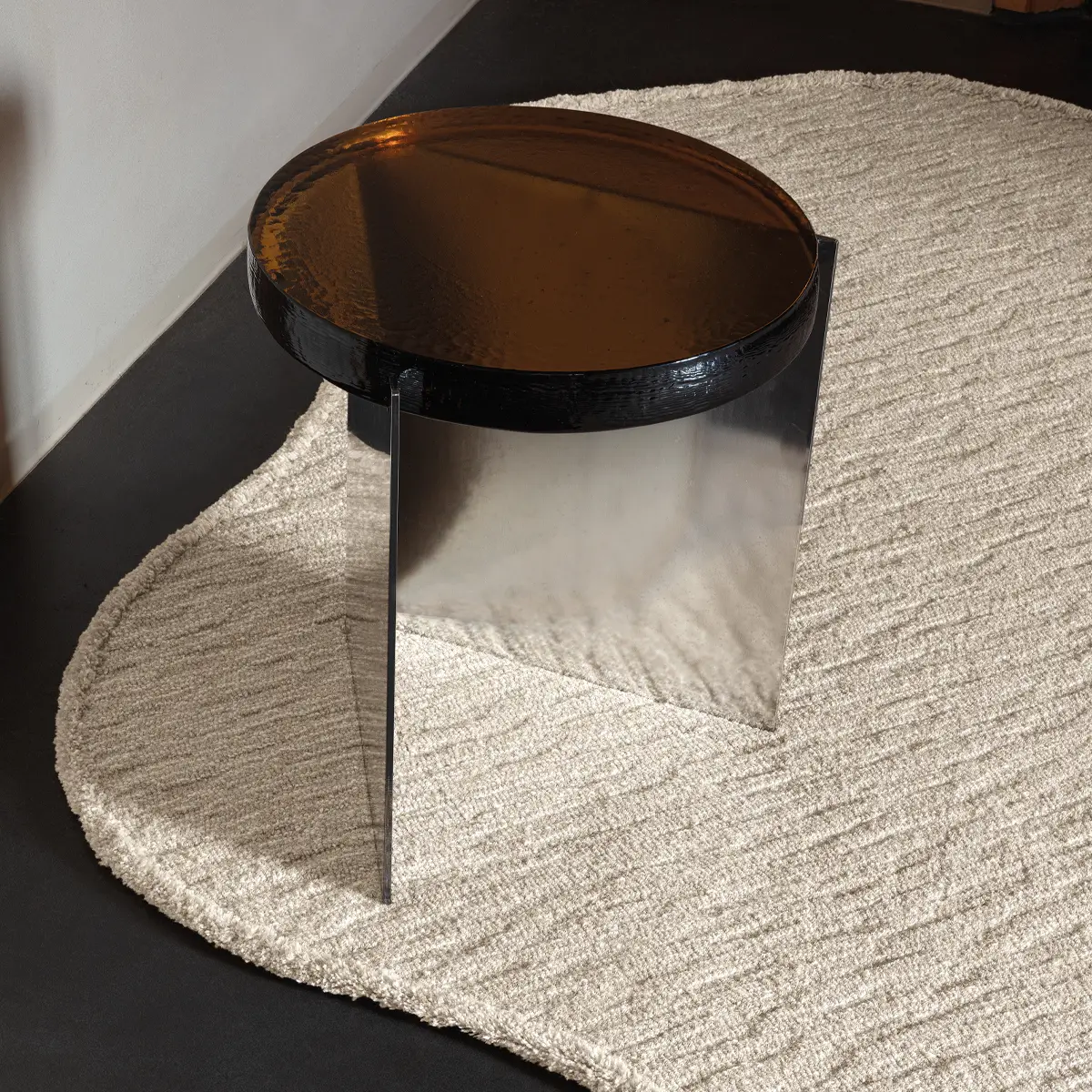 Modern reflective black side table on textured beige rug