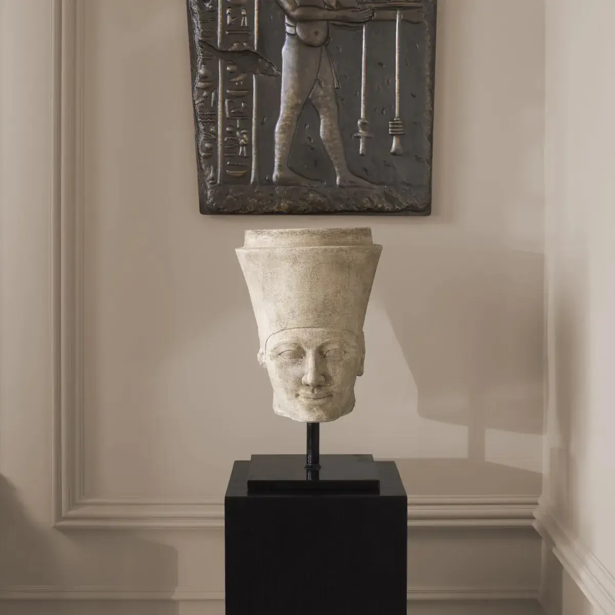 Ancient Egyptian sculpture on pedestal in modern room