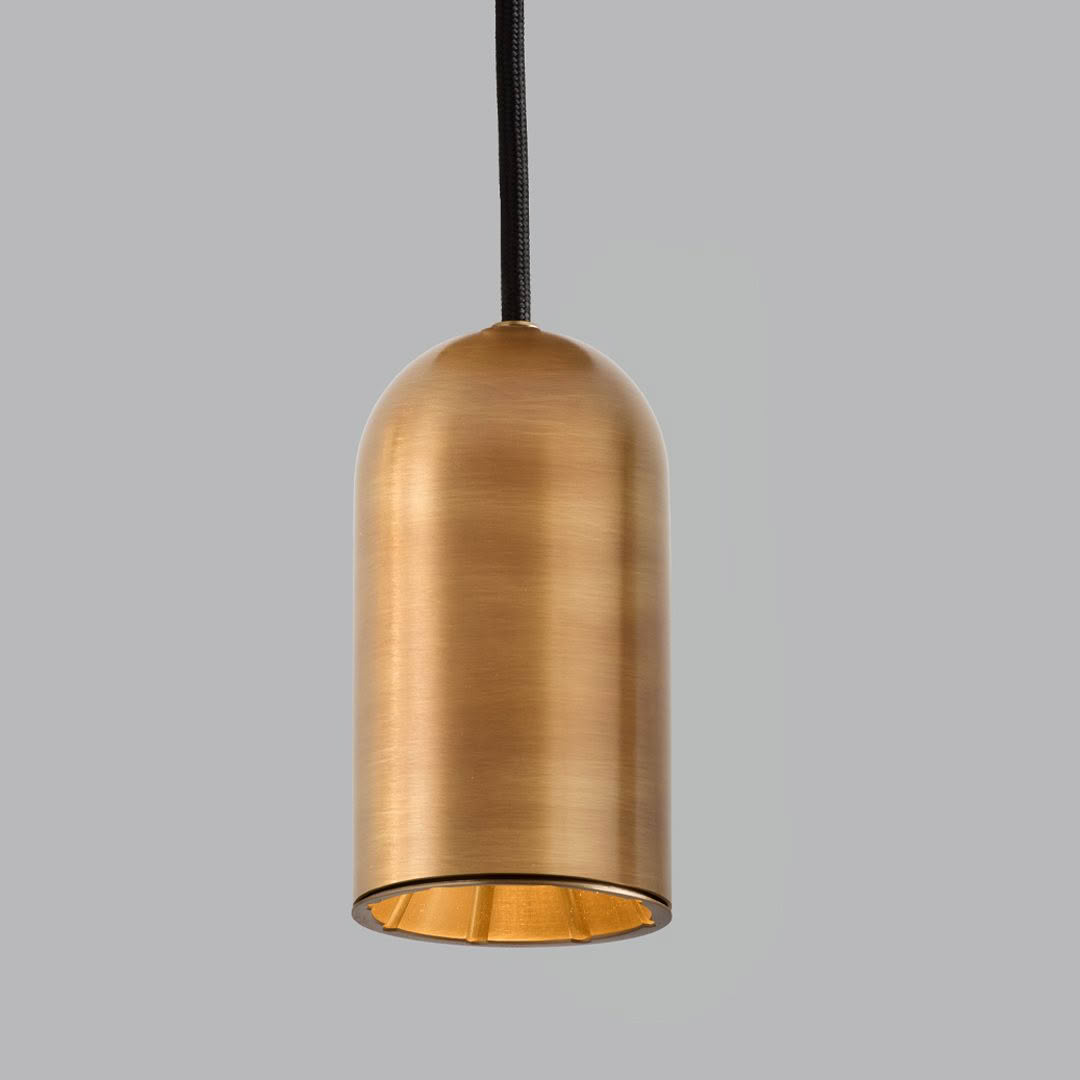 Modern brass pendant light against gray background