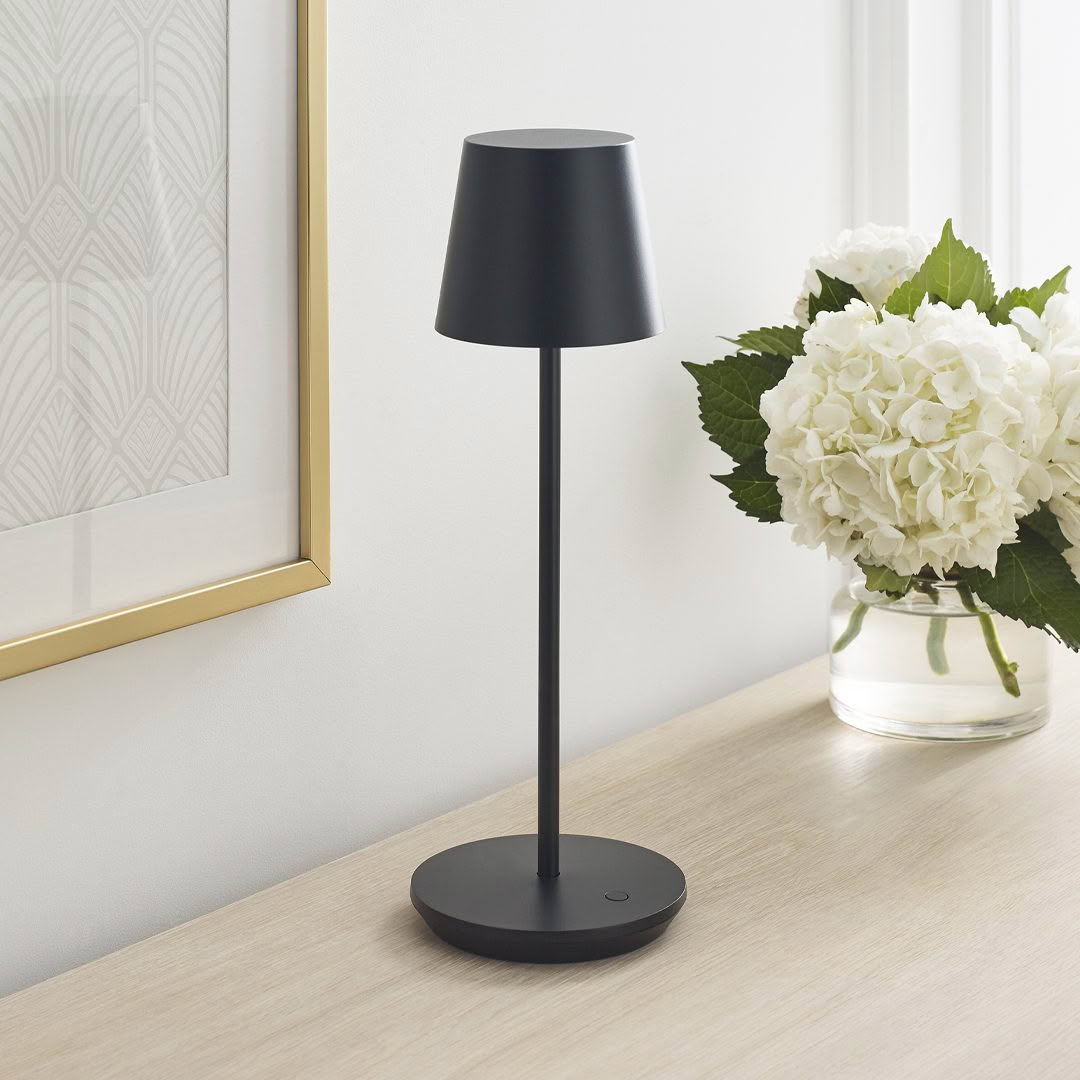 Modern black table lamp next to white hydrangea bouquet