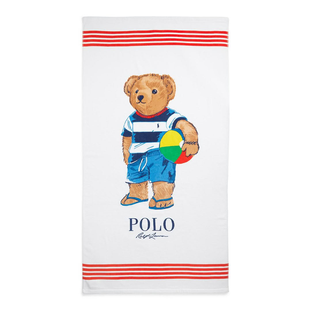 Teddy bear on towel holding colorful beach ball