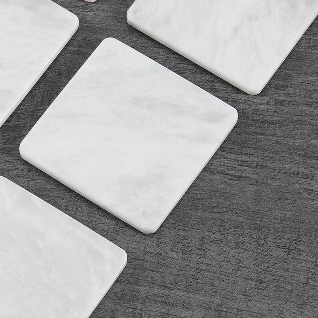 White marble coasters on dark wooden surface