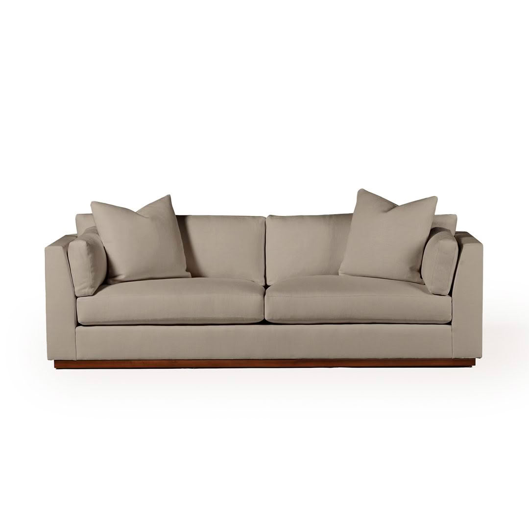 Beige modern sofa with cushions on white background