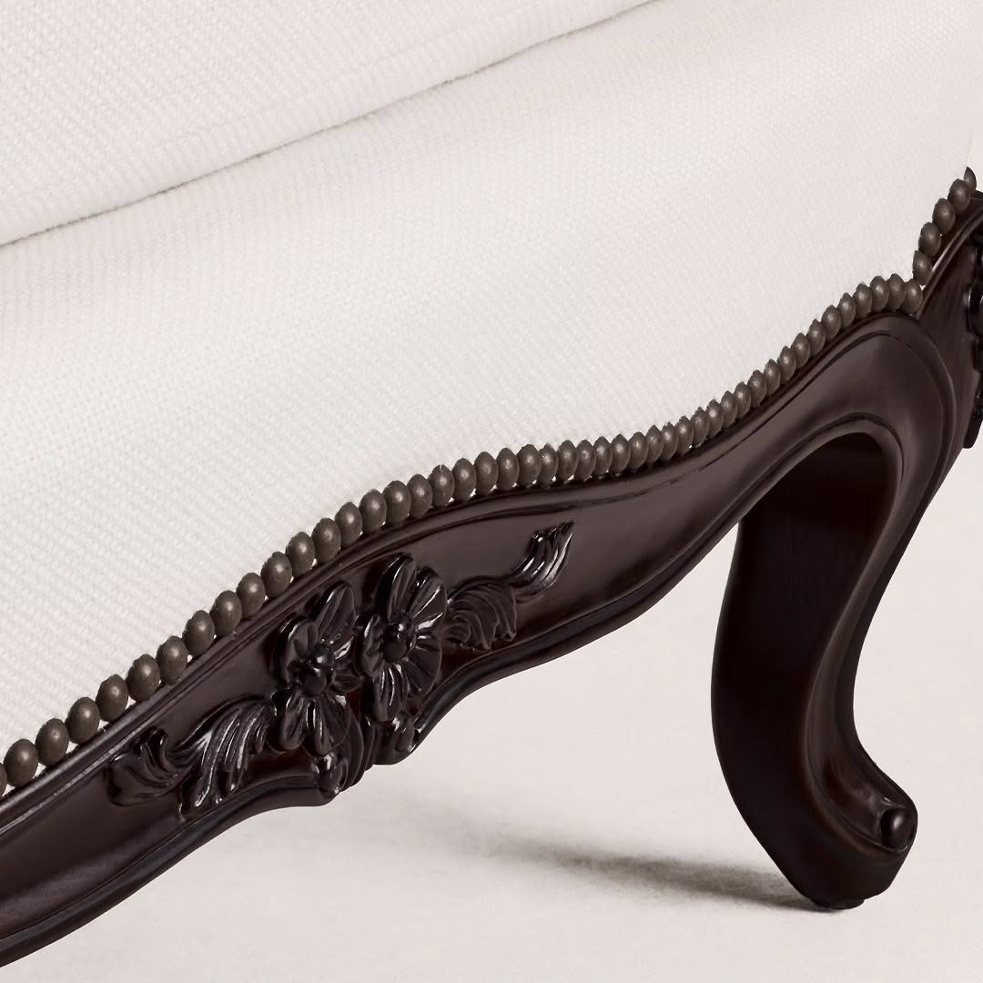 Detailed carving on dark wood sofa leg.