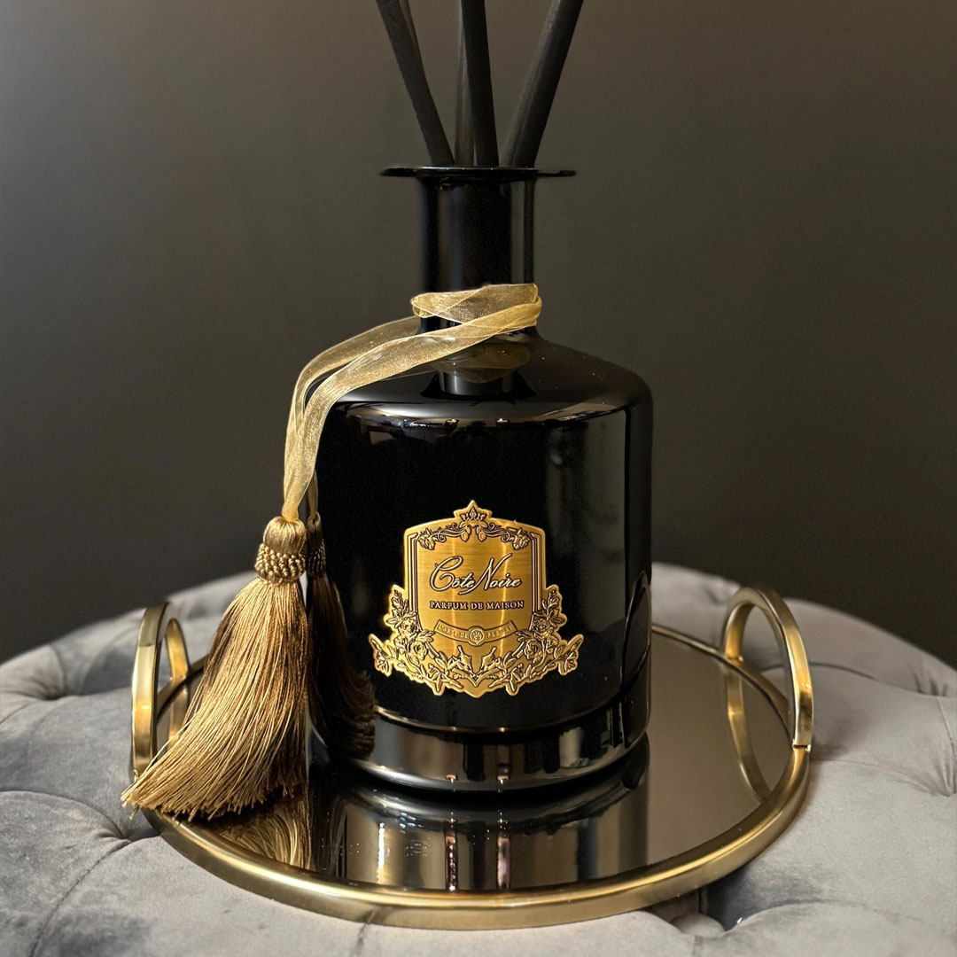 Elegant black reed diffuser on golden tray with tassel