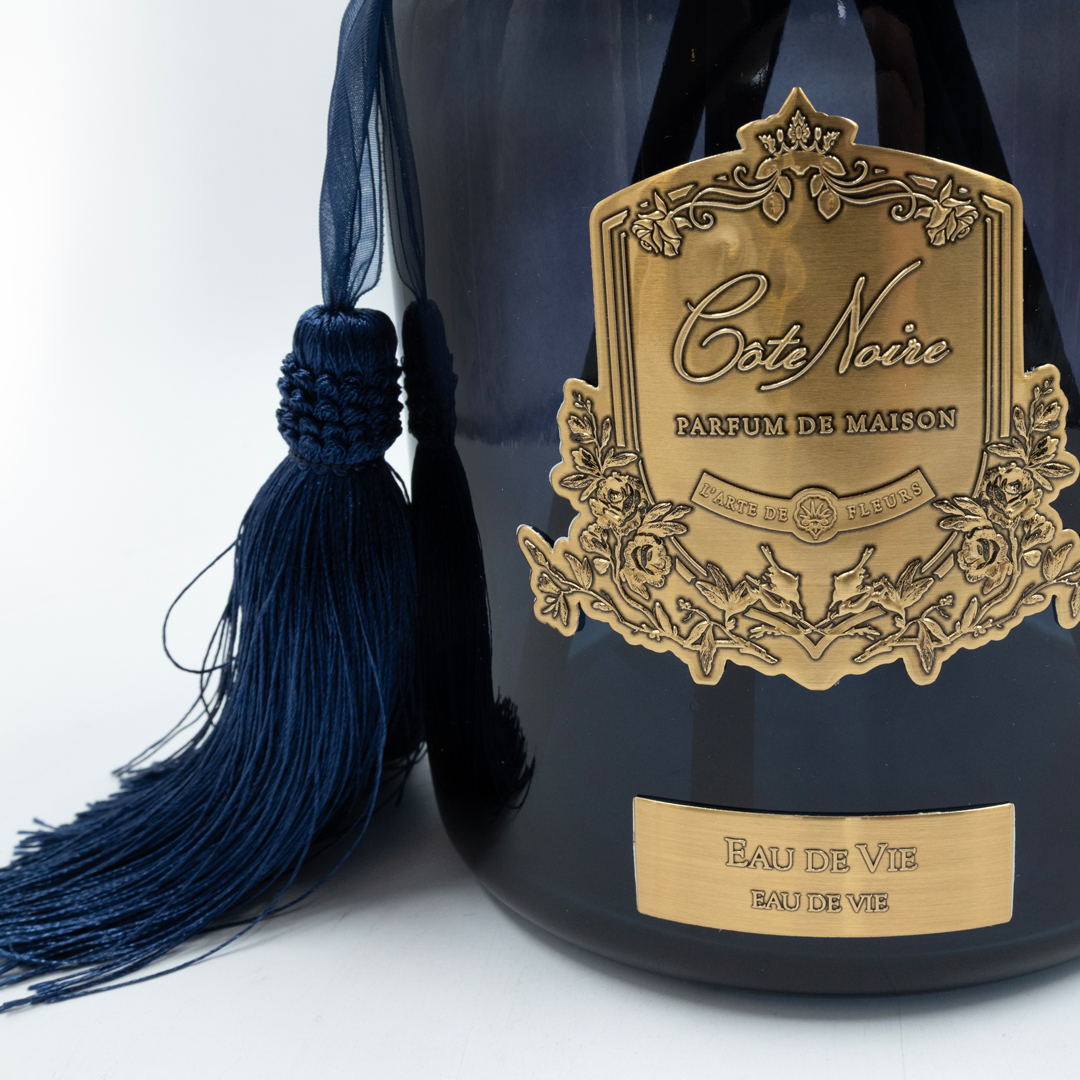 Cote Noire perfume bottle with blue tassel on white background