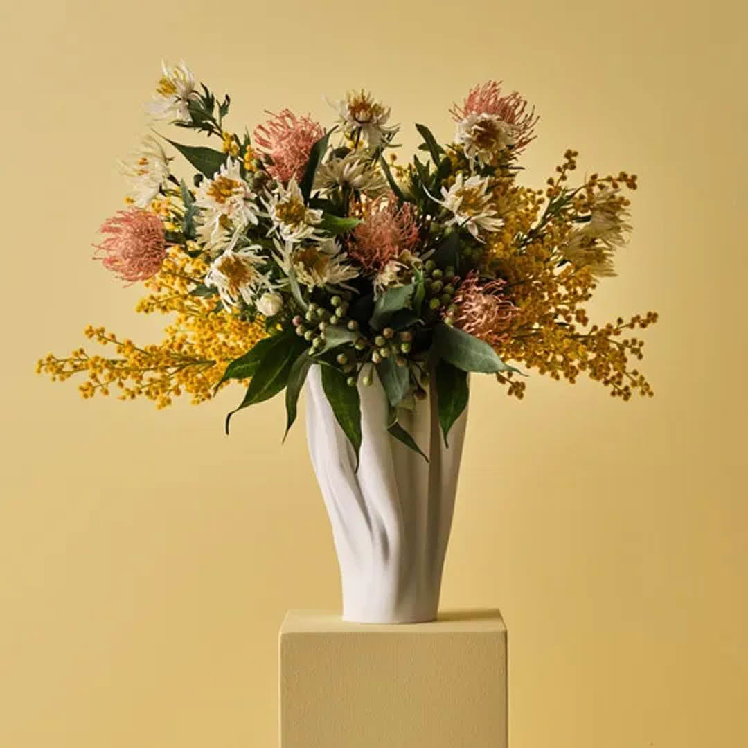 Elegant white vase with assorted colorful wildflowers