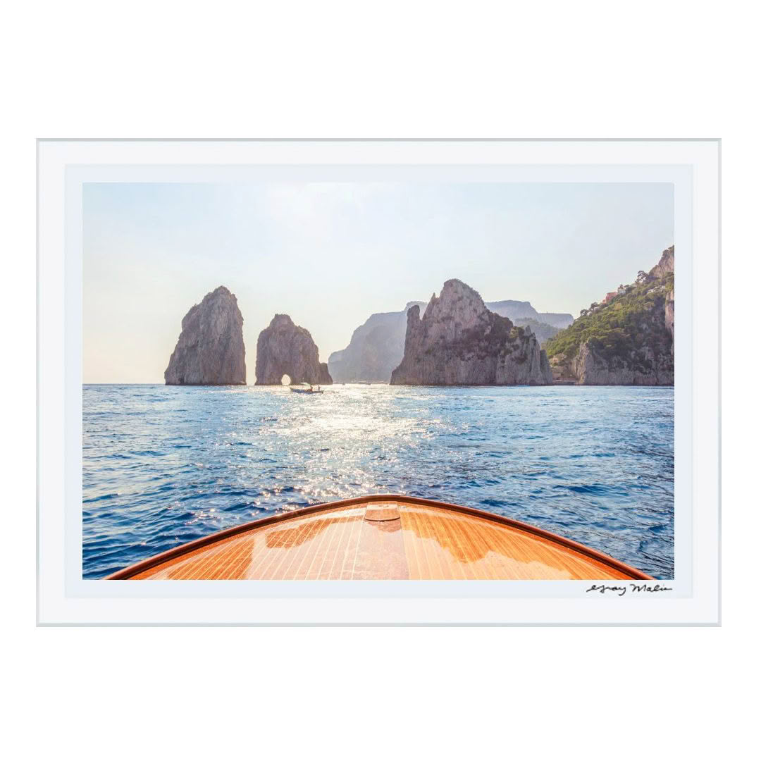 Boat approaching stunning rocky cliffs on sunlit sea