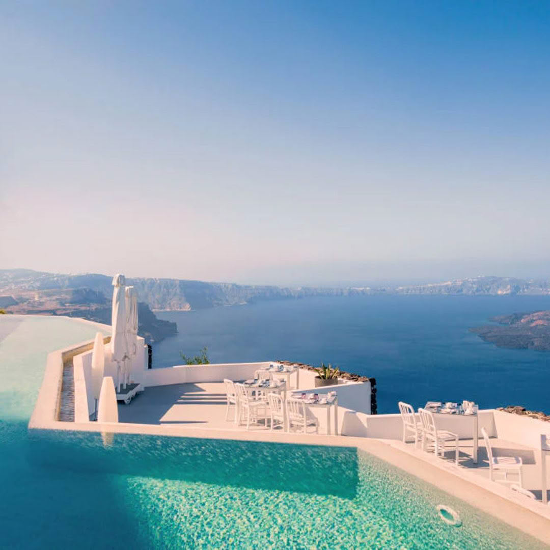 Scenic seaside infinity pool with dining setup