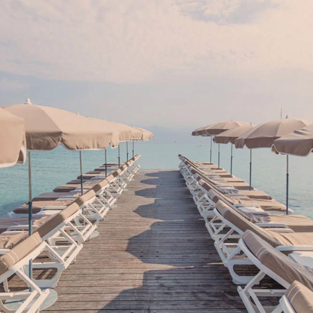 Wooden pier with umbrellas and loungers overlooking sea