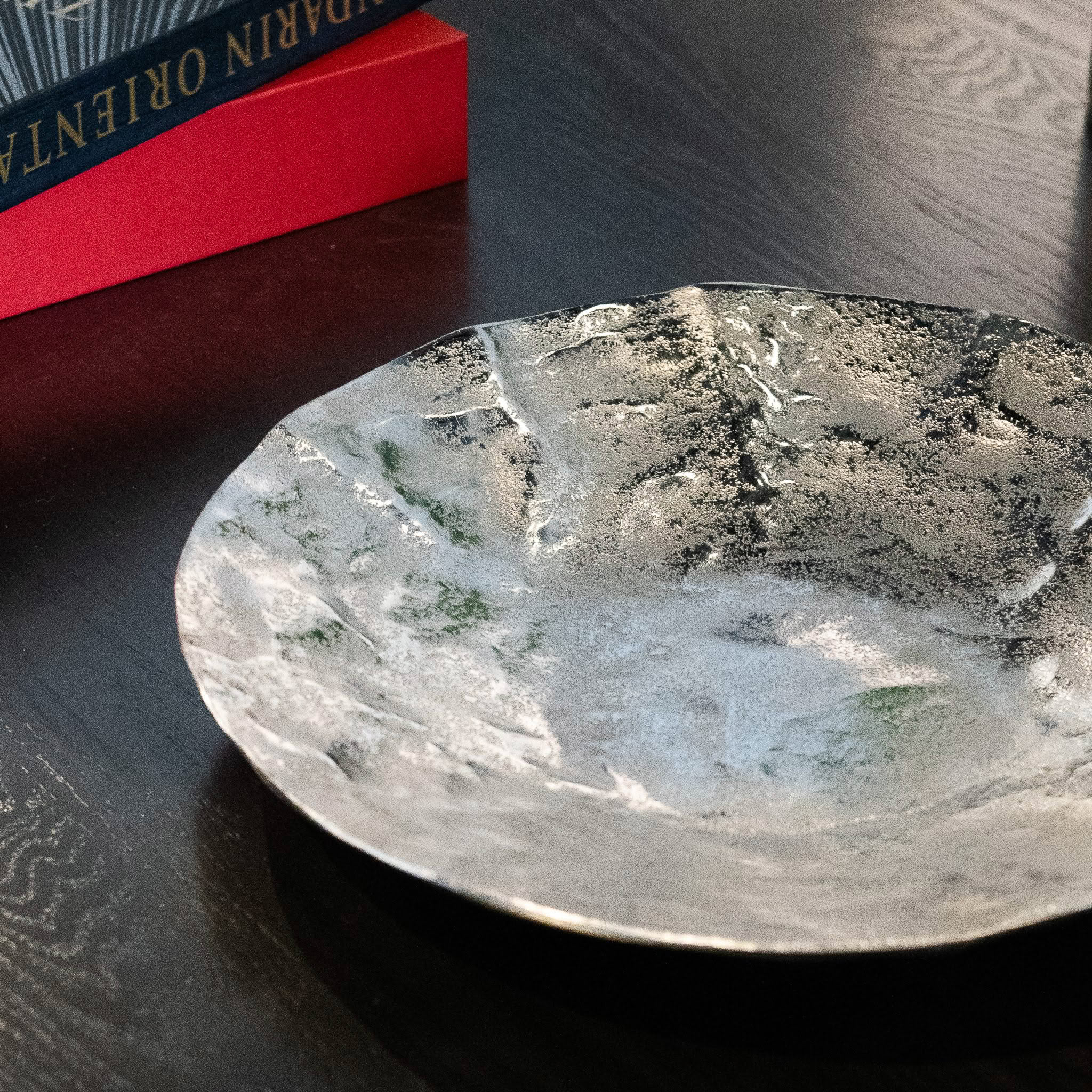 Decorative glass plate with metallic finish on wooden table.